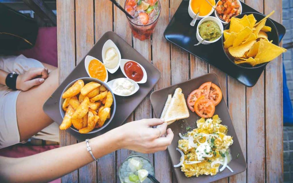 Vemos una imagen de una pequeña mesa de restaurante con diferentes tipos de comida, en referencia a cómo emprender un negocio de comida.