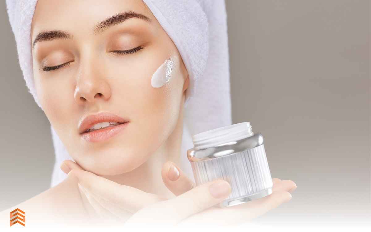 Vemos una imagen de una mujer aplicándose crema facial, en referencia a cómo emprender un negocio de cosméticos y qué tipo de productos vender.